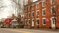 an old red brick building on the corner of a street with trees in front of it