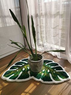 a potted plant sitting on top of a wooden floor next to a curtained window