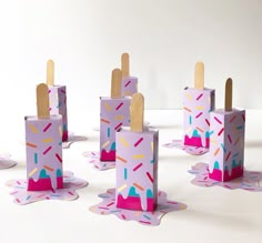 several popsicle boxes with sprinkles and wooden sticks sticking out of them