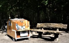 a small food cart sitting next to a wooden bench