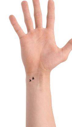 a person's hand with a small bird tattoo on the middle of their palm