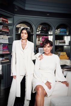 two women sitting on a couch in front of bookshelves