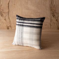 a black and white plaid pillow sitting on top of a wooden table next to a wall