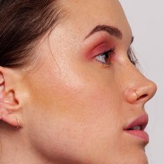 a close up of a woman with ear piercings on her ears and nose, looking off to the side