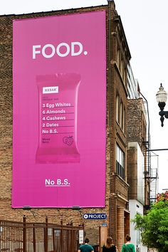 a large advertisement on the side of a brick building with people walking down the street