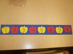 a wooden table topped with an apple themed number line