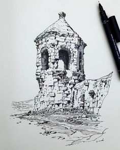 a drawing of an old stone building on paper with a marker next to it and a pen in the foreground