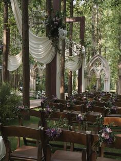 an outdoor wedding setup with wooden chairs and white drapes