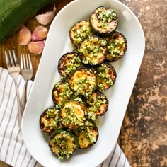 a white plate topped with grilled eggplant and pesto