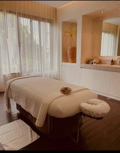 a large white bed sitting in a bedroom next to a window with curtains on it