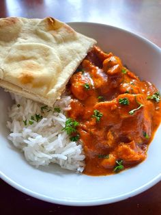 a white plate topped with rice and meat covered in gravy next to pita bread