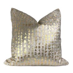 a silver and gold pillow on a white background with some light brown dots in the middle