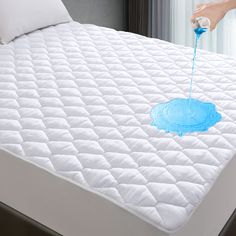 someone is spraying blue paint on a mattress topper that has been made into a bed