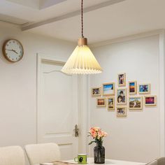 a dining room table and chairs with pictures on the wall behind it, along with a clock