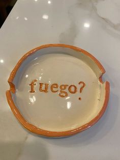 an orange and white plate with the word fuego written on it in cursive writing