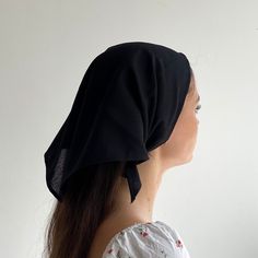 a woman with long hair wearing a black head scarf on top of her head and looking off to the side