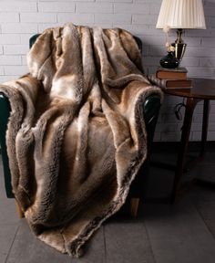 a chair with a blanket on it in front of a brick wall and a lamp