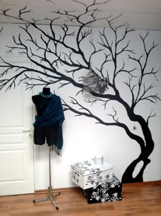 a room with a tree painted on the wall and a coat rack in front of it