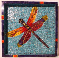 a colorful dragonfly on blue and orange tile in a square frame with small squares around it