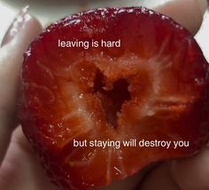 a person holding a piece of fruit with the words leaving is hard but staying will destroy you