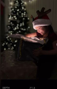 a girl in a santa hat opening a bag