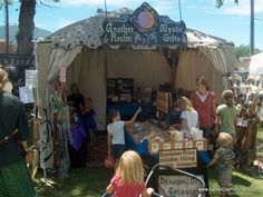 a group of people standing in front of a tent at an outdoor market with signs on it