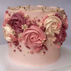 a pink cake decorated with flowers and pearls