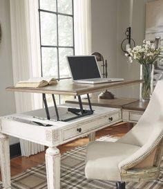 a laptop computer sitting on top of a white desk next to a chair and window