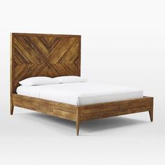 a wooden bed frame with white sheets and pillows