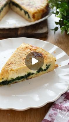 a slice of quiche with spinach on it sitting on a plate next to another dish