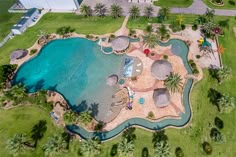 an aerial view of a large pool surrounded by palm trees