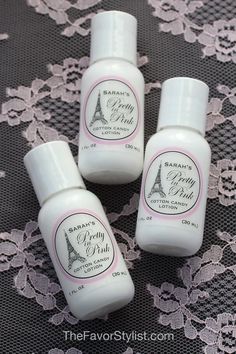 three bottles of lotion sitting on top of a lace covered tablecloth with the eiffel tower in the background