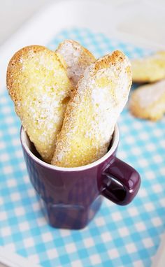 some sugared doughnuts in a purple cup on a blue and white checkered tablecloth