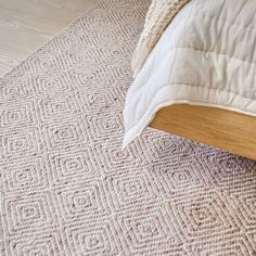 a bed with a white comforter sitting on top of it next to a wooden headboard