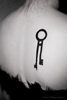 the back of a woman's neck with a key tattoo on it