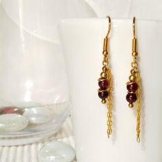 Minimalist, wearable and delicate red garnet and golden earrings. Length: 4 cm. Width: 0.4 cm garnet gemstone. 14k gold plated chain and 14k gold filled round beads. Handmade in Spain. ✩ All our gold earrings are nickel free, cadmiun free and lead free ✩ ⁂ All hooks from NICTE gold plated earrings are 22k gold plated surgical steel and hypoallergenical, nickel and lead free! ⁂ Ideal for a gift. All our products are presented in a white organza bag. ♡ Made with love in Valencia ♡ ---------------- Handmade Burgundy Earrings For Gift, Red Garnet Earrings Gift, Red Garnet Earrings For Gifts, Garnet Drop Earrings As Gift, Red Garnet Wire Wrapped Earrings, Burgundy Jewelry Set With Matching Earrings As Gift, Ruby Earrings With Ear Wire For Gift, Ruby Earrings With Ear Wire As Gift, Gold Garnet Earrings As Gift