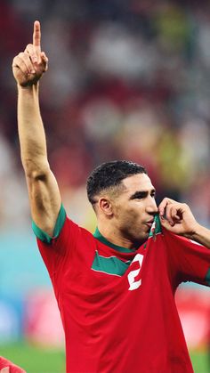 a soccer player with his hand up in the air and one finger raised above his head