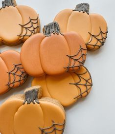 pumpkin cookies decorated with icing and spider webs on white table top next to each other