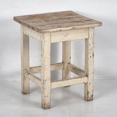 an old white wooden stool on a white floor with no one in the room behind it