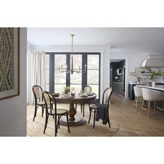 a dining room table with chairs and a chandelier in front of a large window