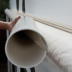 a person is holding a large roll of white paper over the top of a window