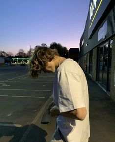 a young man walking down the street in front of a store with his skateboard