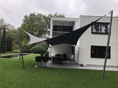 an outdoor dining area in front of a white house with black awnings over it