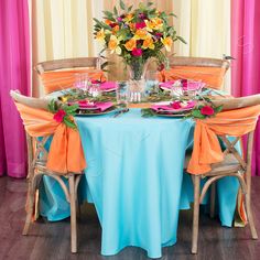 the table is set with colorful flowers and place settings for two people to sit at