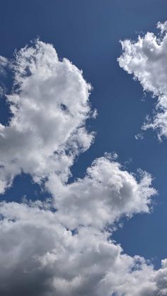 the airplane is flying high in the blue sky with fluffy white clouds above it,