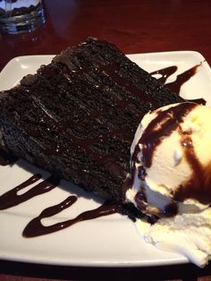 a piece of chocolate cake with ice cream on top and drizzled in chocolate