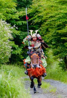 a man riding on the back of a horse down a dirt road