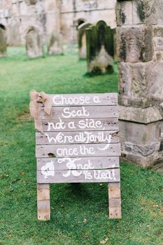 a wooden sign sitting on top of a lush green field