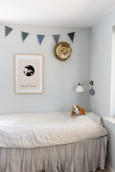 a small bed with a stuffed animal on it's head in a room that has blue walls and white trim