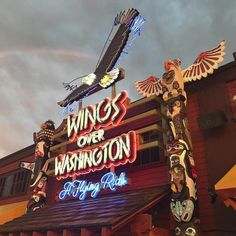 a neon sign that says wings over washington above a building with an eagle statue on top